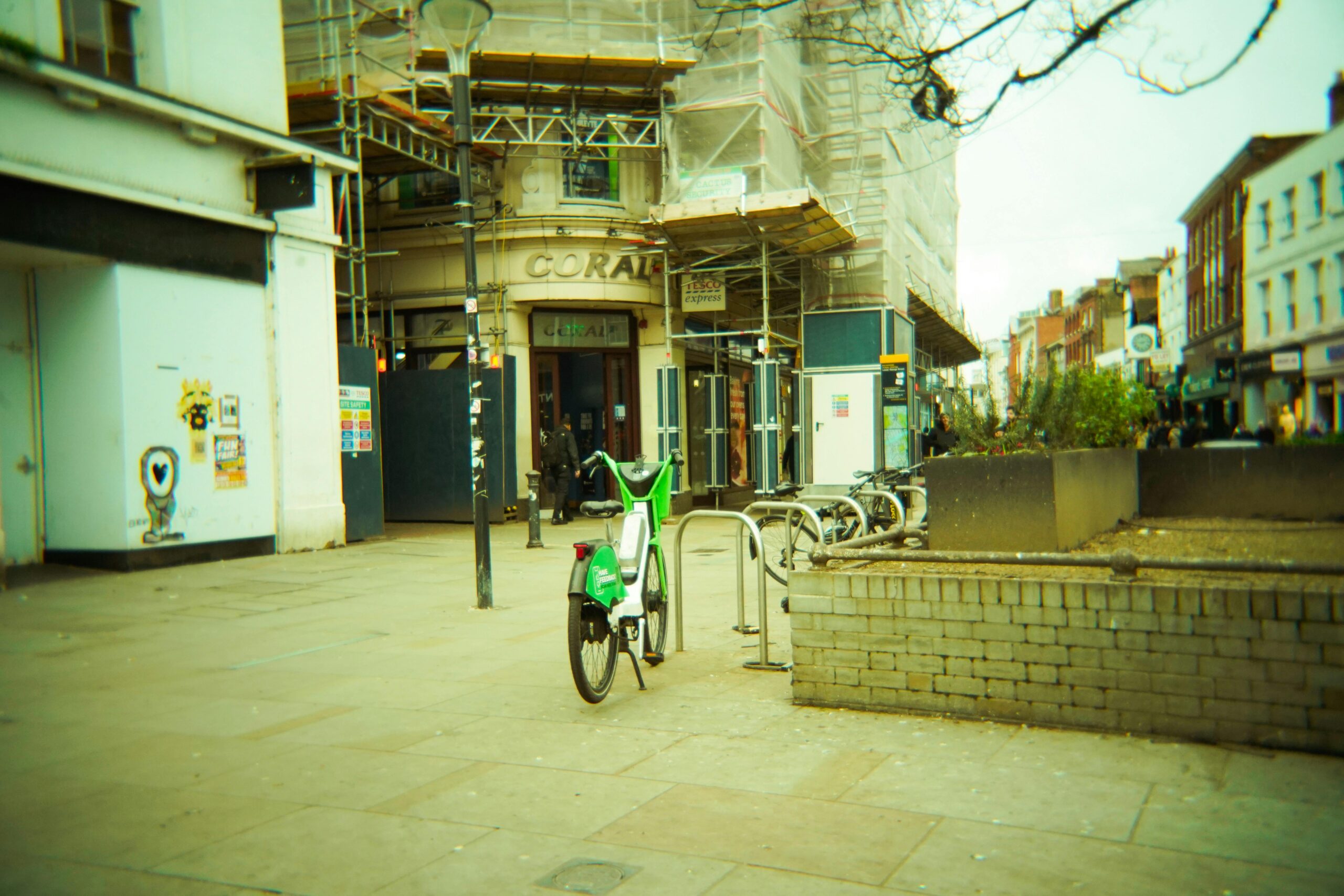 A bright city street featuring bicycle parking with a green bike in focus.