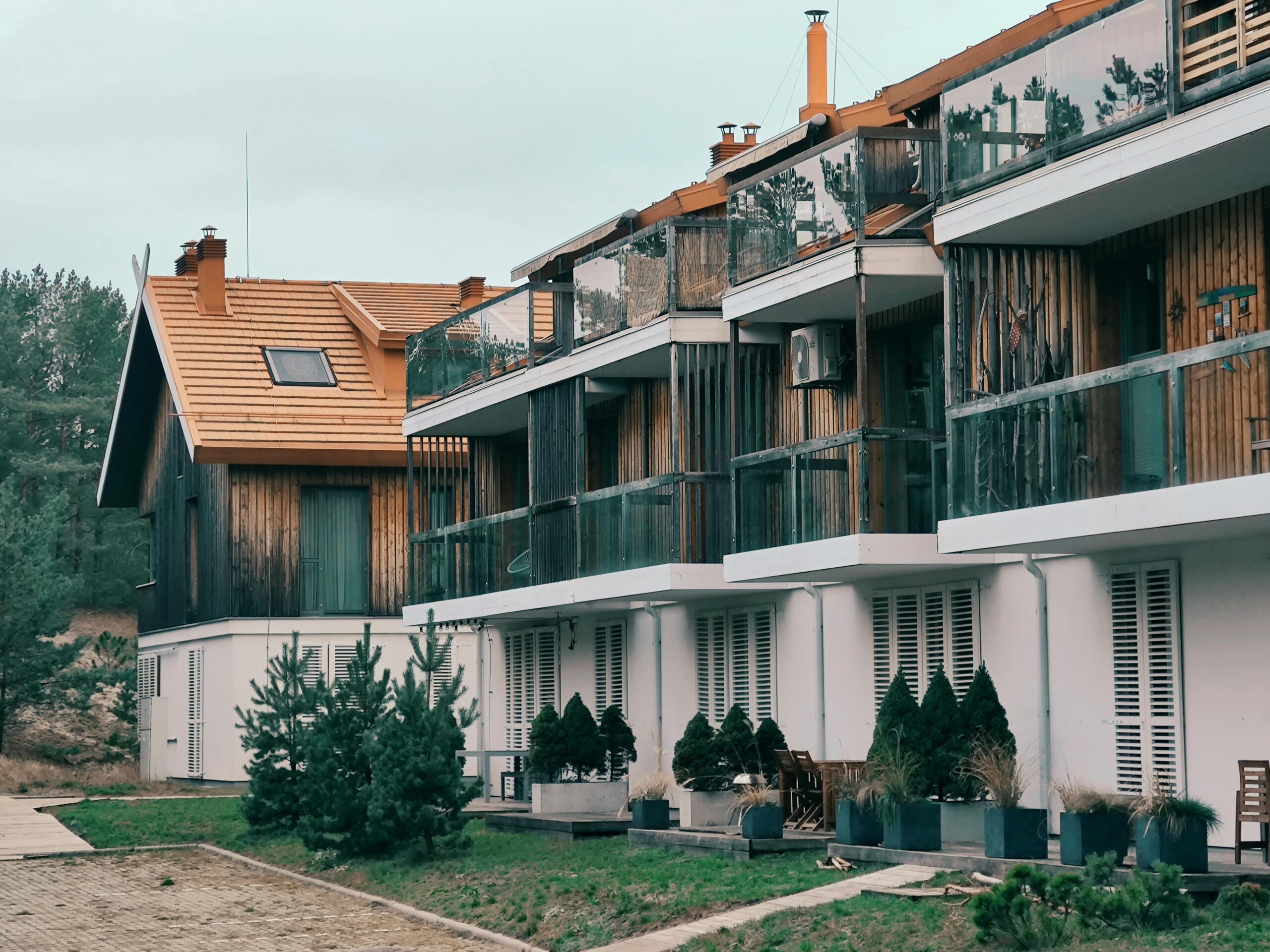Contemporary multi-storey apartments in Nida, Lithuania showcasing wooden balconies and green surroundings.